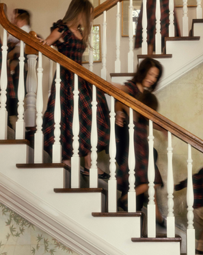 Two women descending a staircase with white railings and wooden steps.