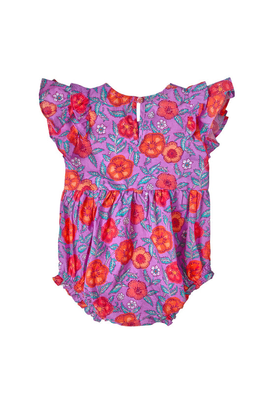 The Ivy City Co Baby Hattie Romper in Thistle Flower Poppy Woodblock features ruffled sleeves and a lively red and orange floral pattern accented with small white flowers, all set against a purple cotton fabric. Displayed on a plain white background, this adorable romper blends soft comfort with standout style for your little one.