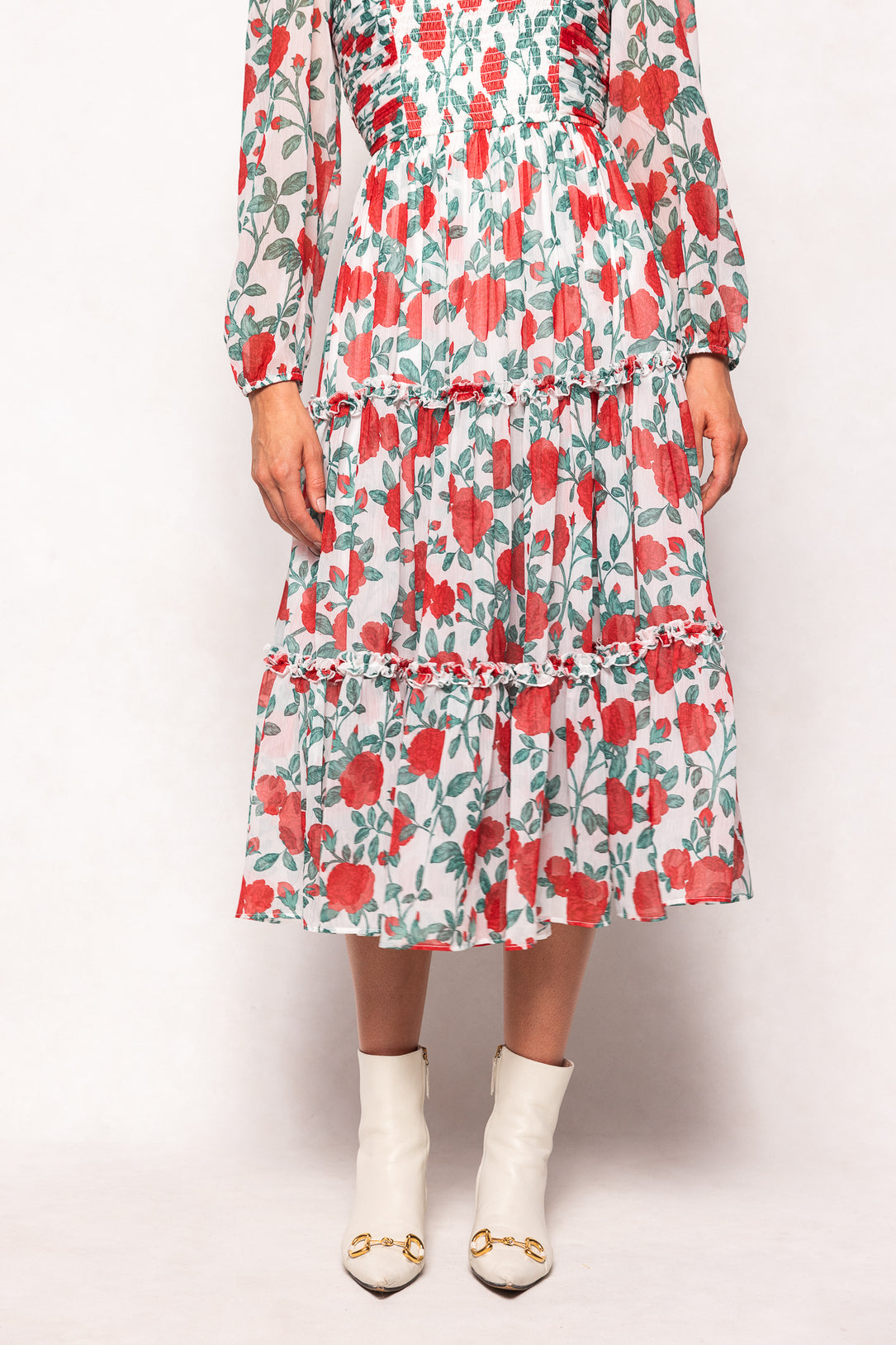 Person wearing a floral dress with red and green pattern on a white background