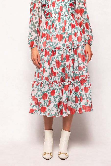 Person wearing a floral dress with red and green pattern on a white background