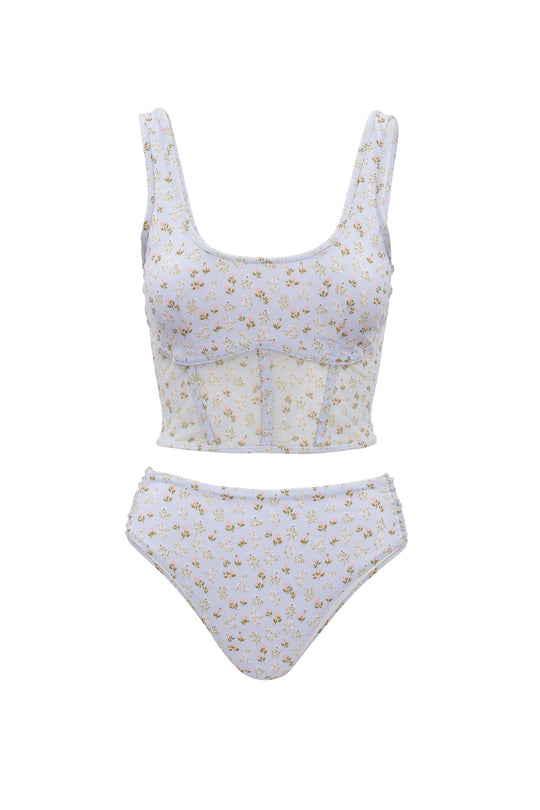 The Ivy City Co Mid Rise Ruched Bottom in Blue Ditsy Floral is a two-piece swimsuit featuring a crop tank-style top with wide straps and high-waisted, cheeky bottoms for a playful, comfortable fit.