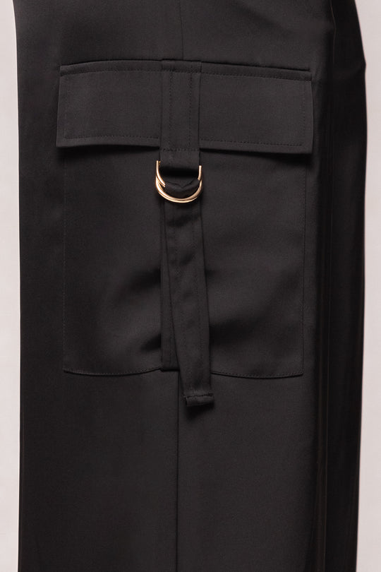 Black coat with a gold buckle on a neutral background