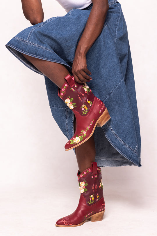 Red embroidered boots worn with a denim skirt on a white background