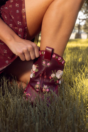Person wearing a floral embroidered shoe in a grassy outdoor setting