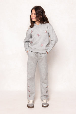 a young girl in a grey sweatsuit against a white background