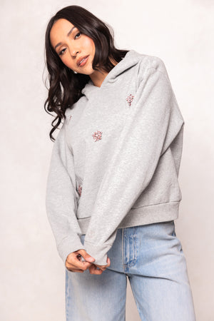 Girl in a grey hoodie and jeans against a white background