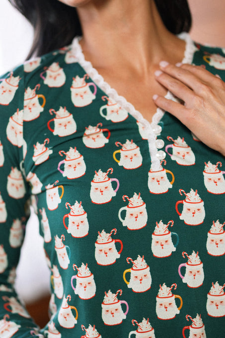 Someone wears the So Soft Henley Pajama Set in Very Merry Santa by Ivy City Co—featuring festive mug prints, soft cotton-modal fabric, lace trim, and white buttons at the neckline.