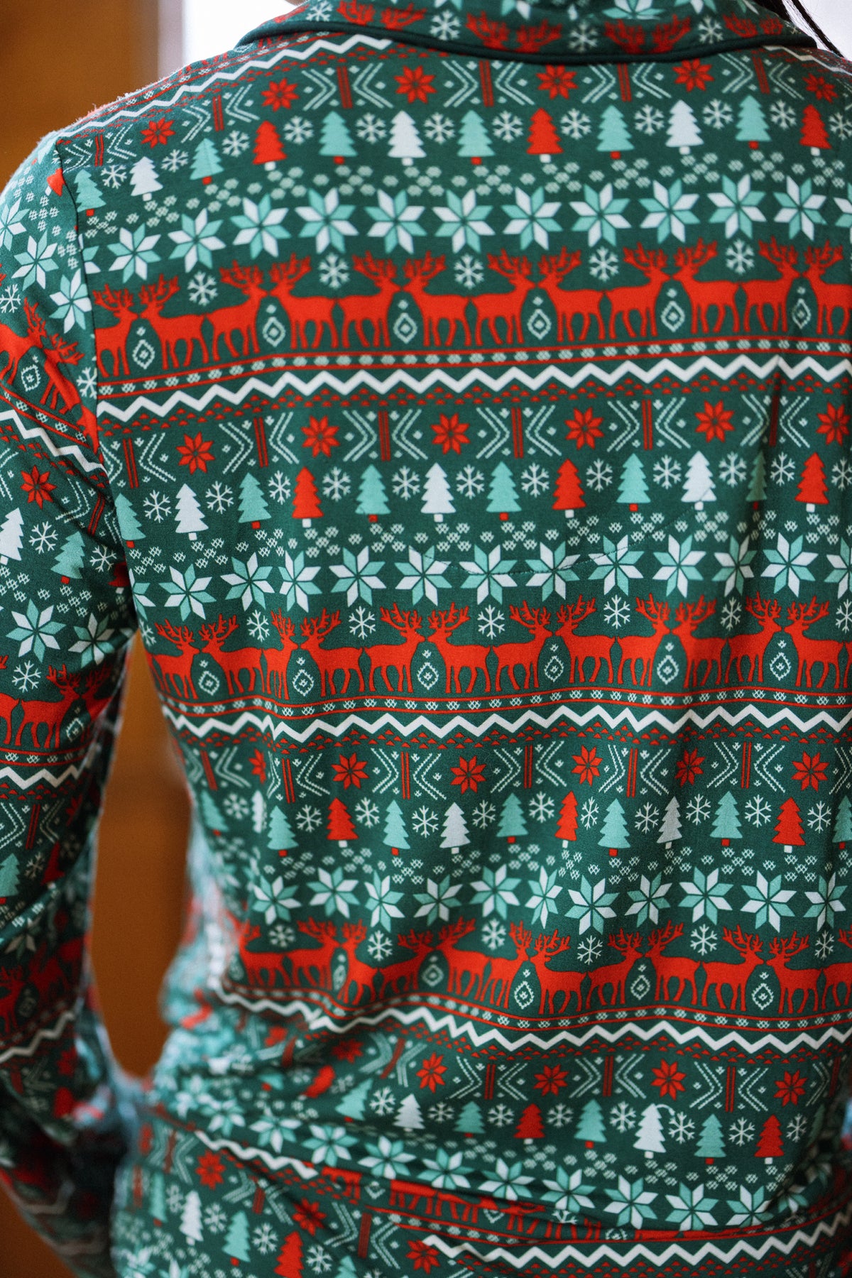 Person wearing a green and red holiday sweater with festive patterns, as cozy as the So Soft Pajama Set in Alpine Noel from Ivy City Co. The image highlights the back of the sweater.