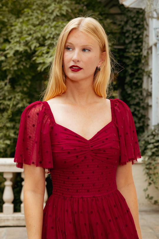 Woman wearing a red dress with a blurred outdoor background