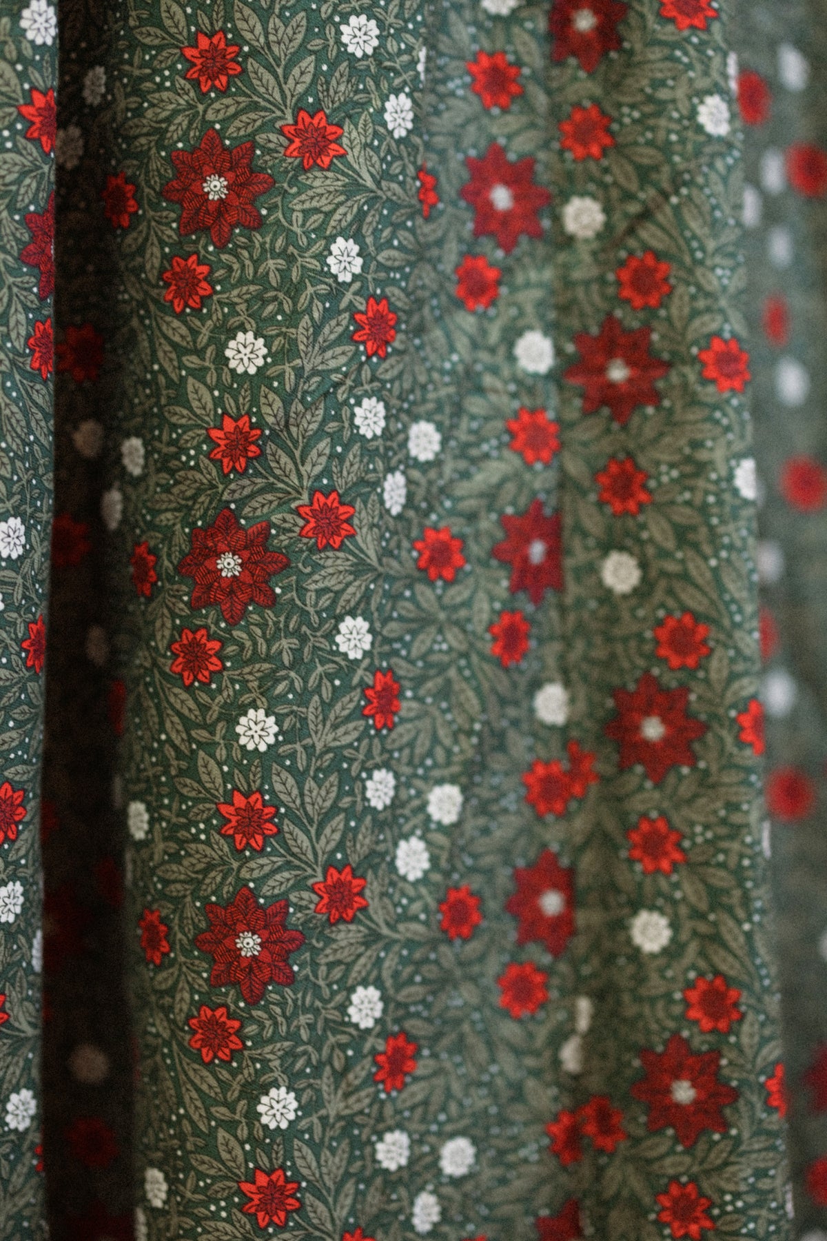 The Sophia Dress in Evergreen Merry Ditsy by Ivy City Co features green fabric adorned with a dense, decorative print of small red and white flowers on leafy vine backgrounds—an ideal choice for a vintage-inspired or festive holiday look.