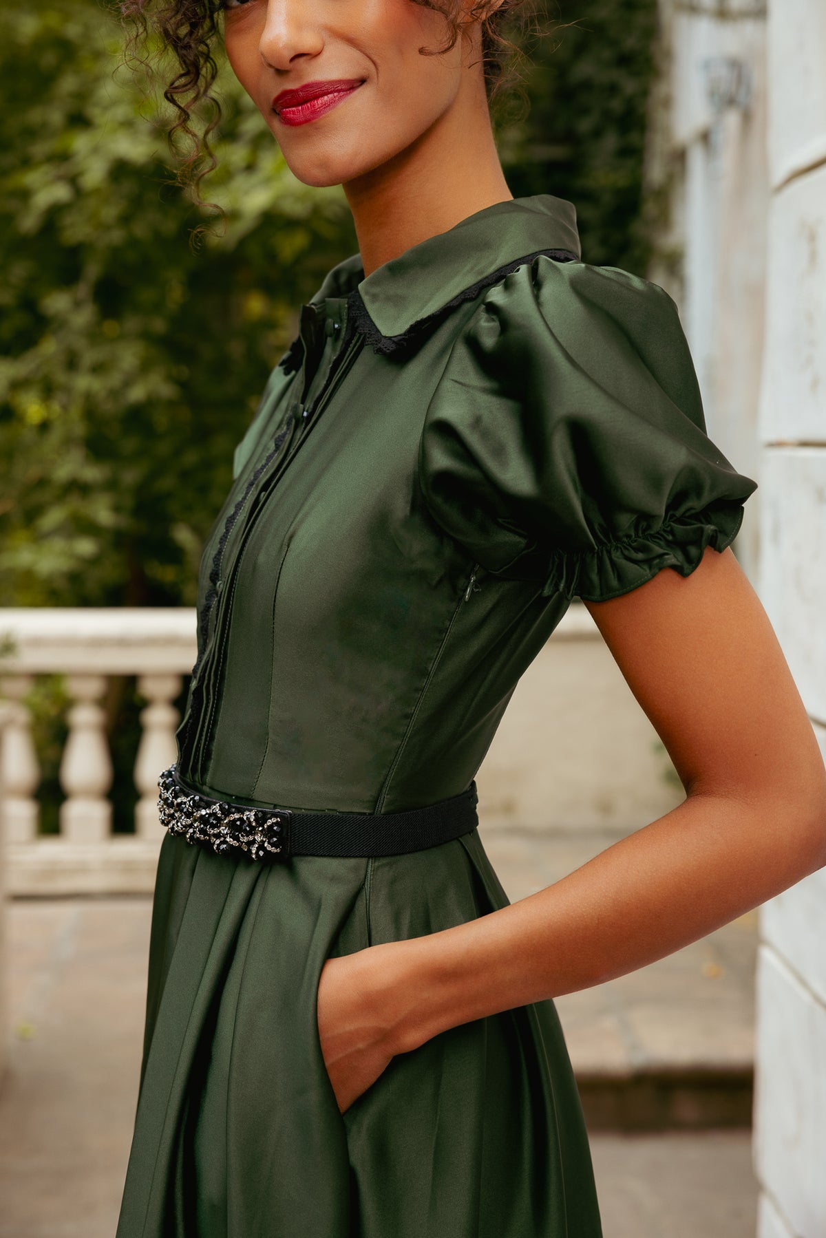 Woman wearing a green dress with ruffled sleeves in an outdoor setting