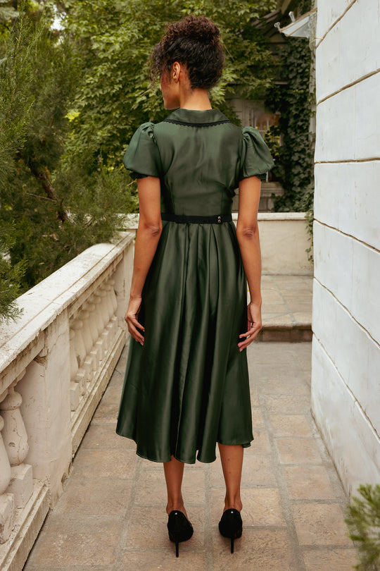 Woman in a green dress standing on a stone path with trees in the background