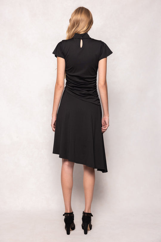 Woman wearing a black dress with a cutout back on a light background