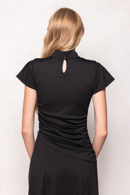 Woman wearing a black dress with a unique back design on a white background