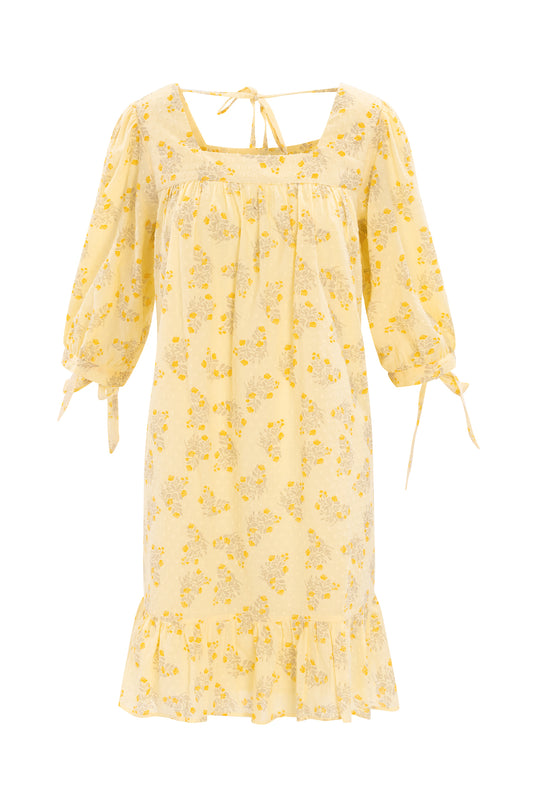 The Sunny Dress in Yellow Floral by Ivy City Co is a light yellow, knee-length swiss dot cotton dress with puffed tie sleeves, square neckline with back tie, ruffled hem, and maternity-friendly comfort and style.
