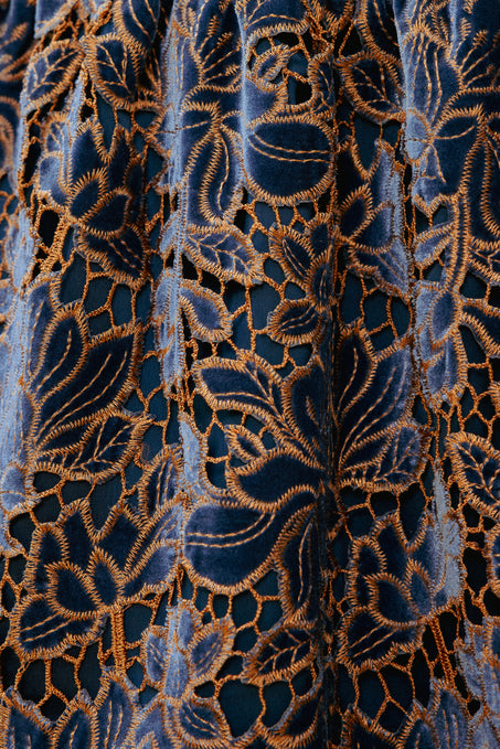 Close-up of a blue fabric with intricate gold embroidery