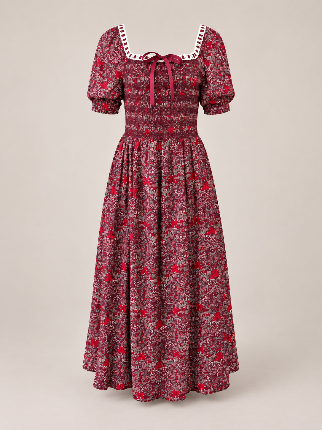 The Sunday Best Dress in Garnet Ribboned Garden by Ivy City Co is a long holiday dress featuring a floral print, puffed short sleeves, a smocked bodice, and a square neckline adorned with white lace and finished with a burgundy ribbon bow at the center.