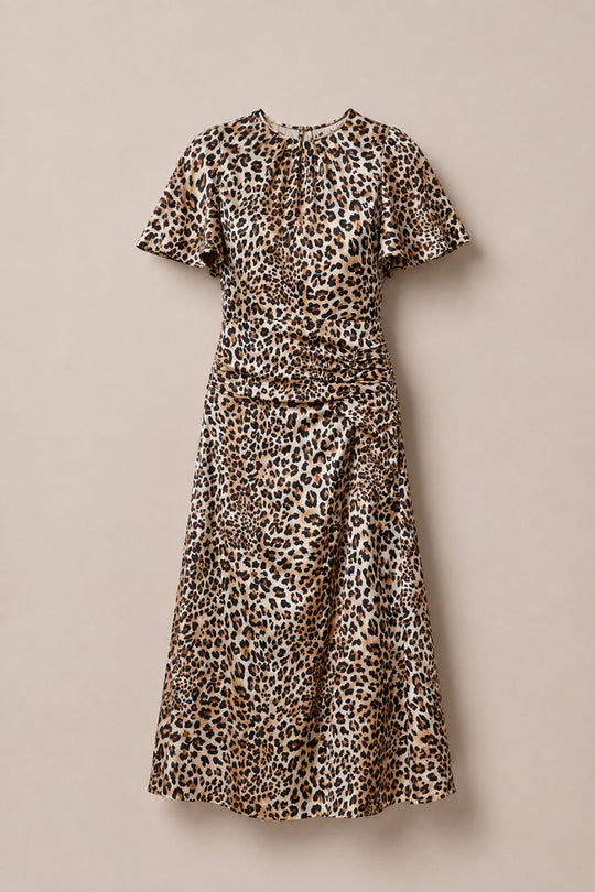 The Tallulah Dress in Leopard by Ivy City Co is a short-sleeved, calf-length dress with a brown and black leopard print, featuring a ruched bodice and gathered waist, displayed against a plain beige background.