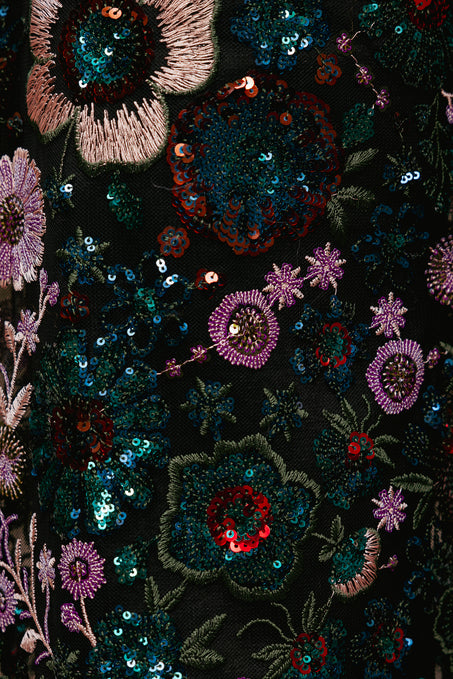 Close-up of a black fabric with colorful floral embroidery and sequins.
