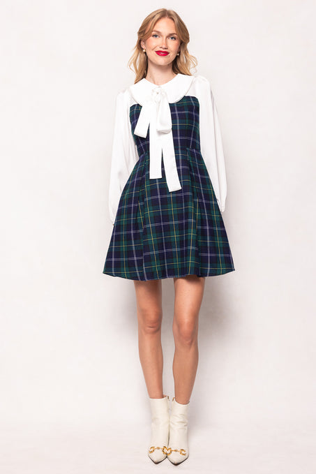 Woman wearing a plaid dress with a white blouse and white shoes on a white background