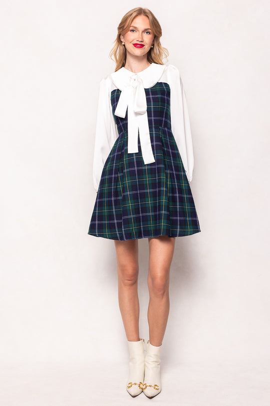 Woman wearing a plaid dress with a white blouse and white shoes on a white background