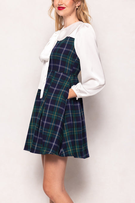 Woman wearing a plaid dress over a white blouse on a plain background
