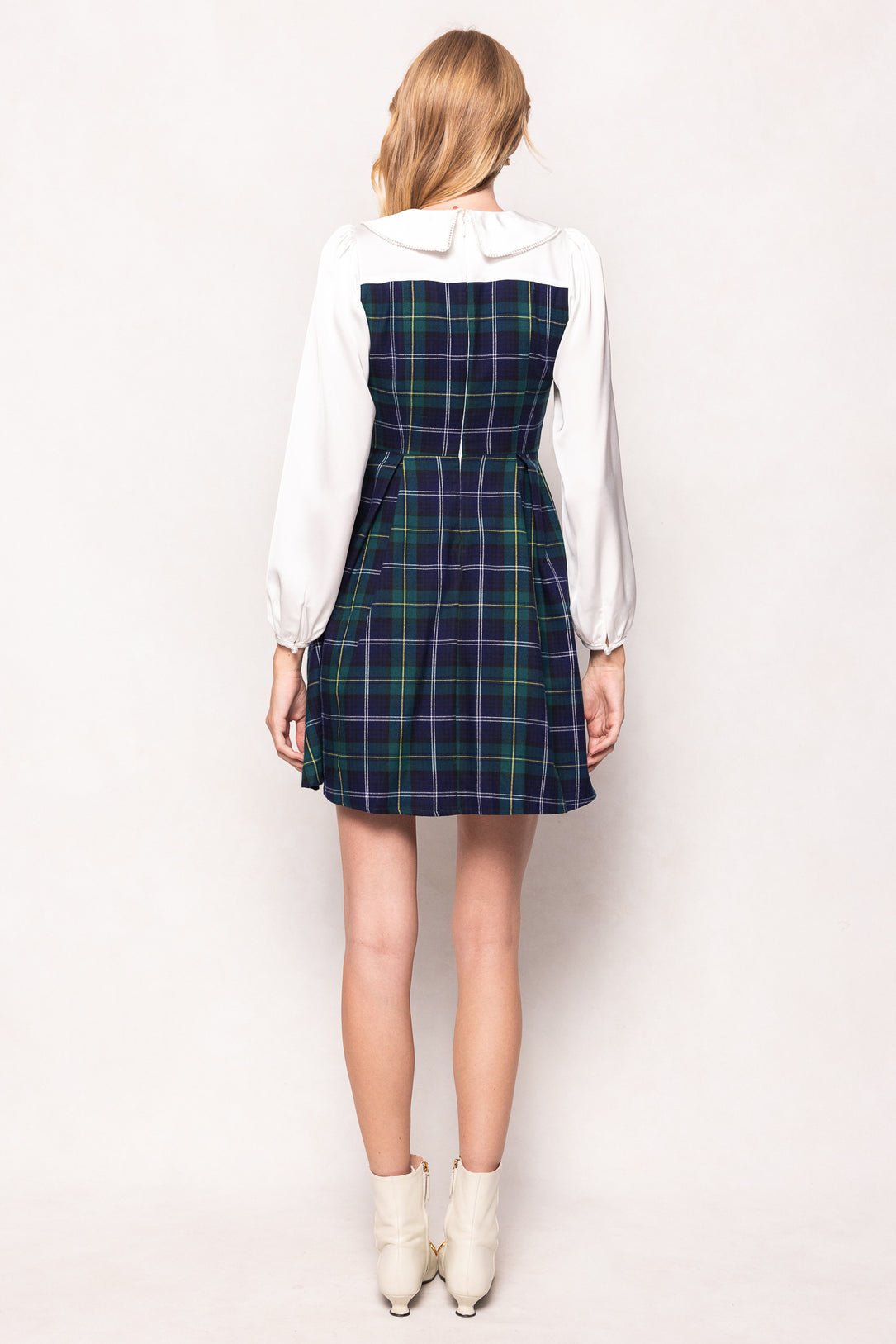 Person wearing a plaid dress over a white shirt on a white background