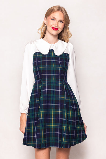 Woman wearing a plaid dress over a white shirt with a Peter Pan collar on a white background