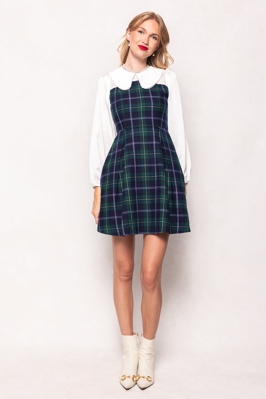 Woman wearing a plaid dress over a white shirt on a white background