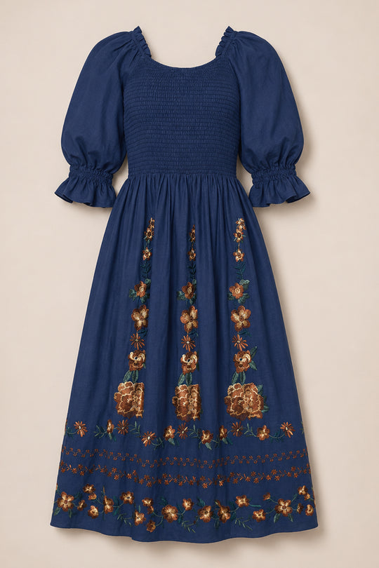 The Teagan Dress in Navy Embroidered Fall Floral by Ivy City Co is a blue midi dress featuring puffed sleeves, a smocked bodice, and vibrant floral embroidery along the skirt and hem. Designed to be effortlessly stylish and maternity-friendly, it combines comfort with elegance for any occasion.