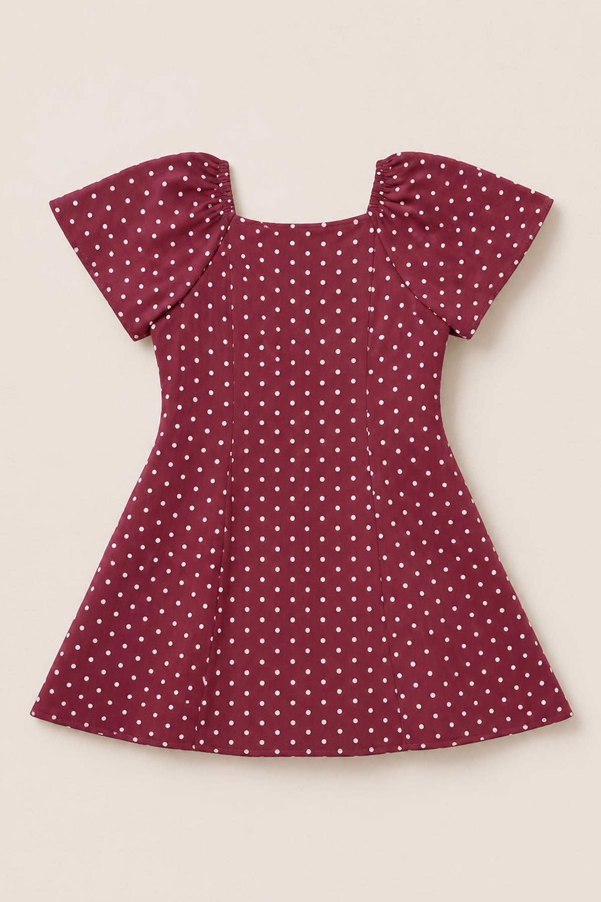 A Teen Blakely Dress in Cranberry Dainty Dot by Ivy City Co, featuring white polka dots, puffed petal sleeves, and a fitted waist, is laid flat on a light background.