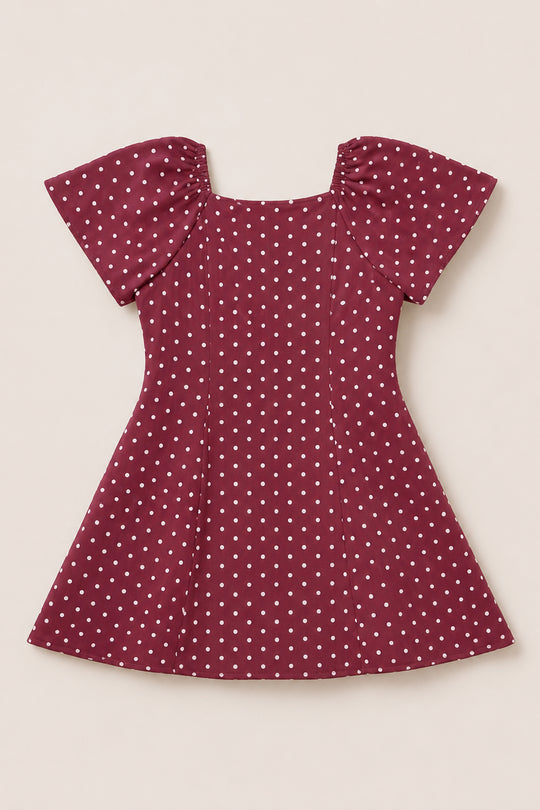 A Teen Blakely Dress in Cranberry Dainty Dot by Ivy City Co, featuring white polka dots, puffed petal sleeves, and a fitted waist, is laid flat on a light background.
