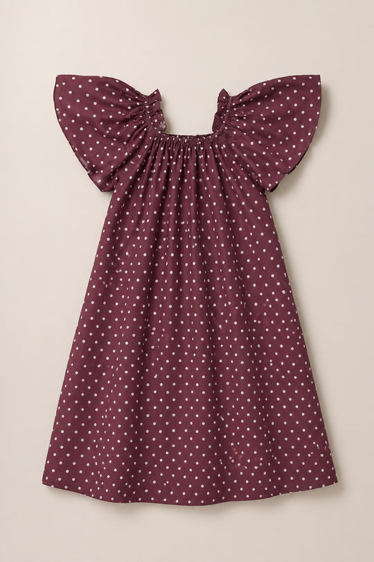 The Ivy City Co Teen Blakely Dress in Aubergine Ditsy Dot features short, flutter sleeves and a gathered neckline with a smocked bodice, adorned with white polka dots and displayed on a neutral background.