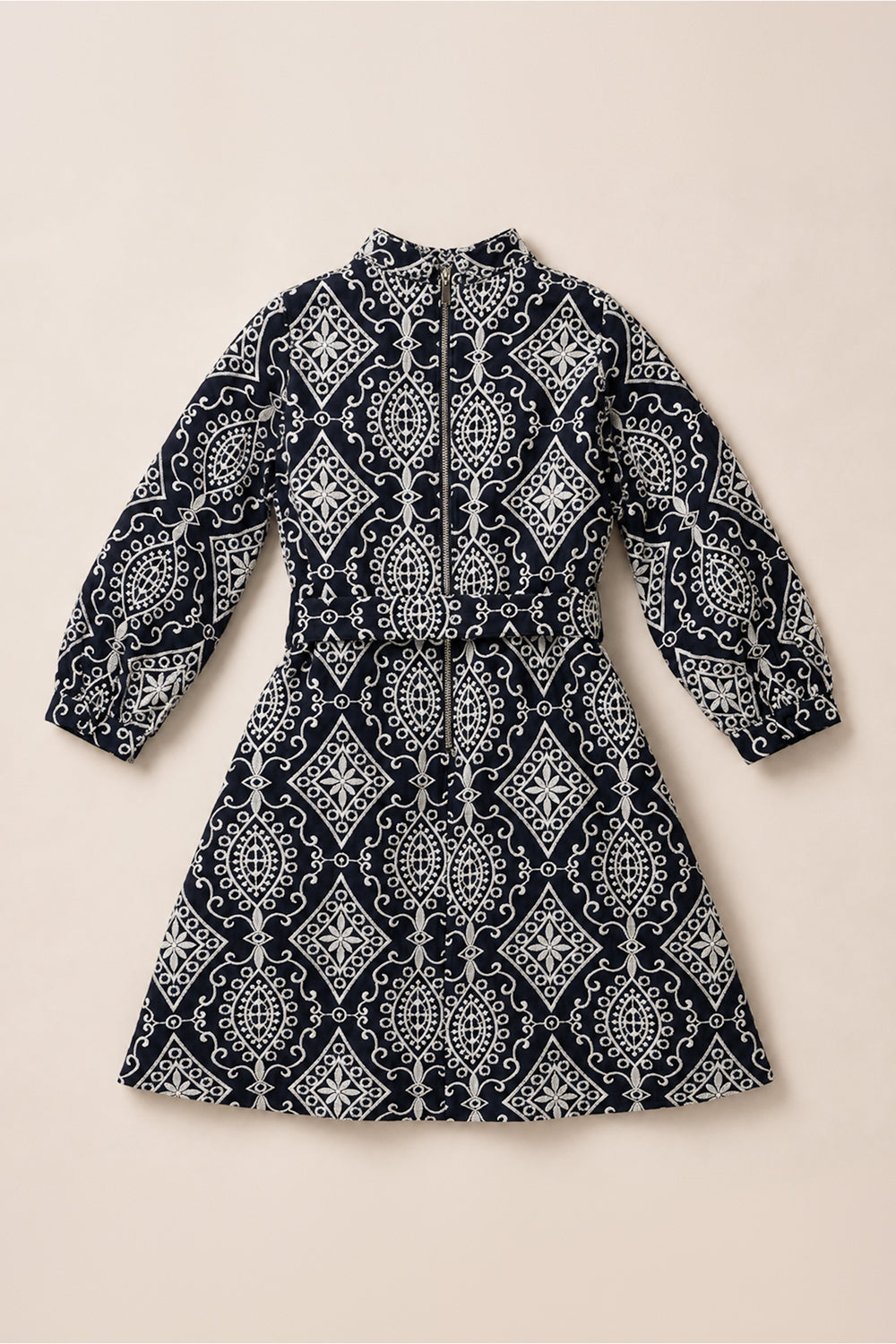 Navy blue long-sleeve Teen Clover Dress in Midnight Tile by Ivy City Co, featuring a white geometric and floral pattern, belted at the waist and displayed flat on a light beige background. This elegant midi-length dress effortlessly combines style and comfort.