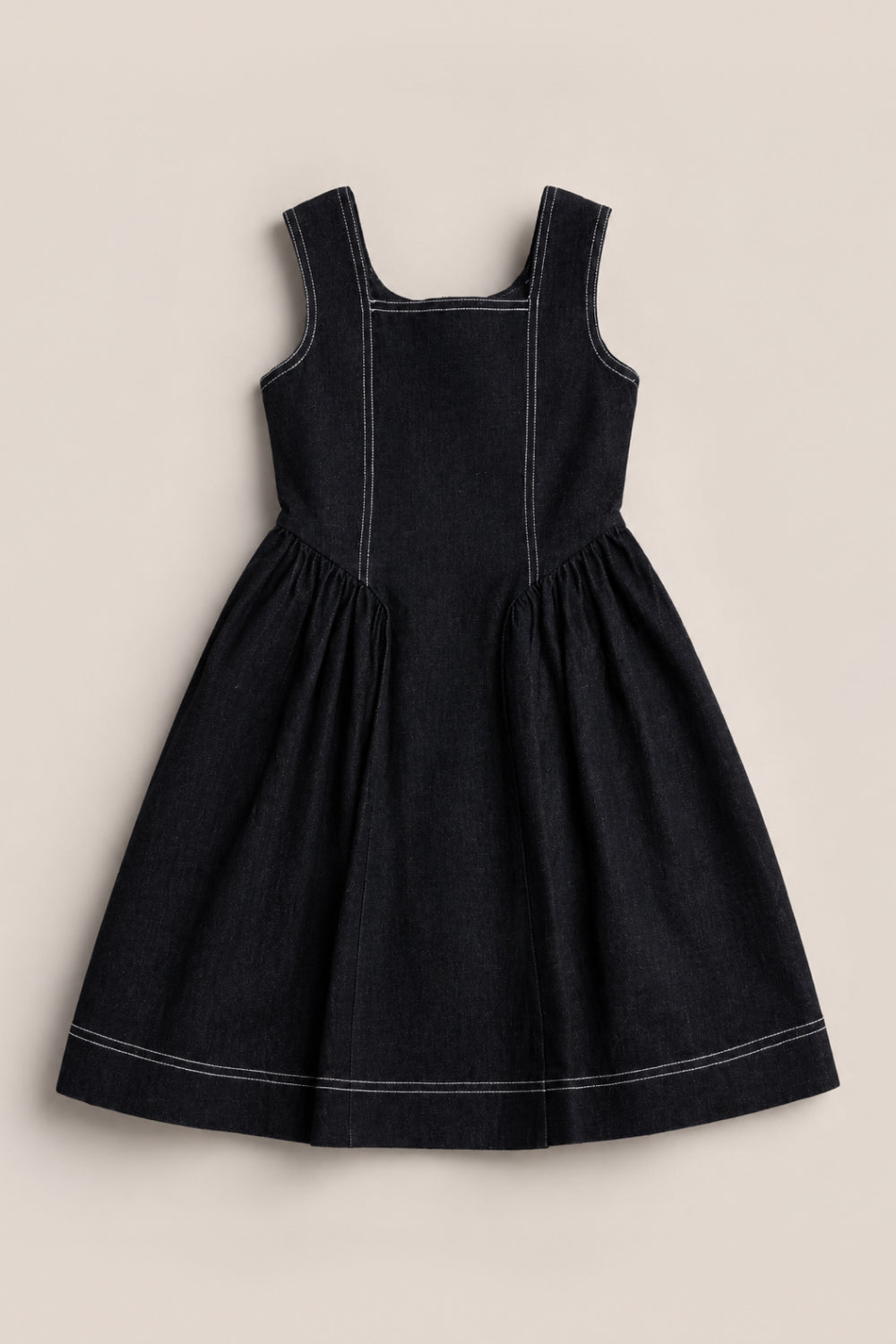 A Teen Edith Dress in Black by Ivy City Co is displayed flat on a light background; it features a sleeveless design, white stitching, square neckline, fitted bodice, and a gathered knee-length skirt.