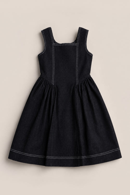 A Teen Edith Dress in Black by Ivy City Co is displayed flat on a light background; it features a sleeveless design, white stitching, square neckline, fitted bodice, and a gathered knee-length skirt.