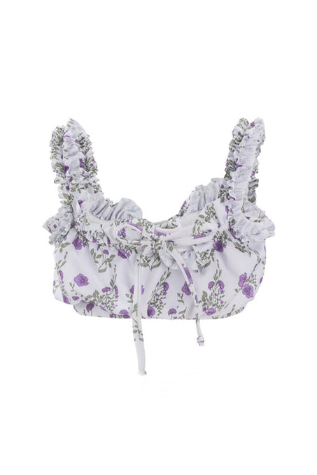 The Mini Thea Top in Maeve Floral by Ivy City Co is a cropped, sleeveless white swim top with purple floral prints, ruffled shoulder straps, and a front tie—perfect for girls’ swimwear collections.