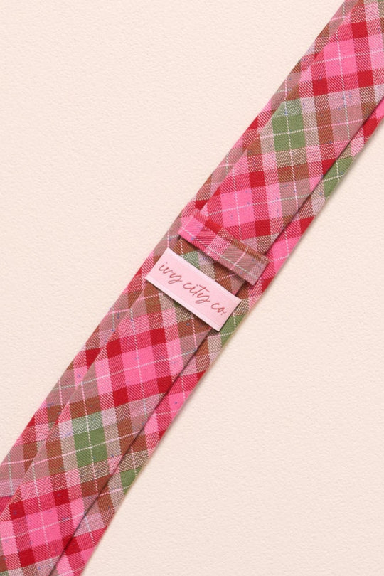 Plaid tie with a pink label on a beige background