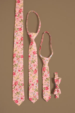 Four Ivy City Co “Ties in Pink Vintage Poppies”—long, medium, child-sized neckties, and a small bowtie—are displayed vertically on tan, perfect for family matching or spring photos with their charming rose pattern.