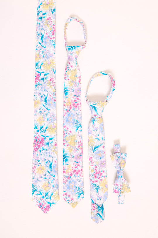 An assortment of floral ties in various sizes laying flat against a white backdrop