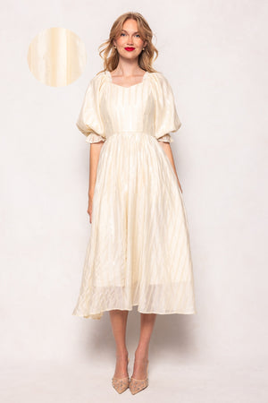 Woman wearing a white dress with sheer sleeves against a plain background