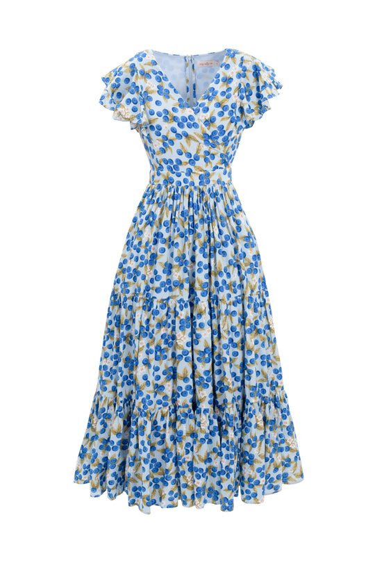 The Trixie Dress in Blueberry by Ivy City Co features a blue and yellow floral print, short flutter sleeves, a V-neckline, gathered waist, and tiered cotton maxi skirt.