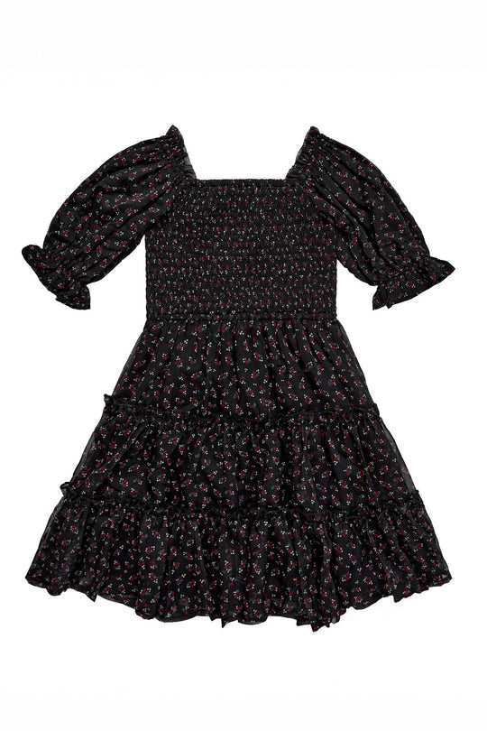 The Mini Madeline Dress in Black Ditsy Floral by Ivy City Co is a short-sleeved, black mini dress featuring a smocked bodice, puffed sleeves, and a tiered ruffle skirt. This charming dress is adorned with a small ditsy floral print in red and white.
