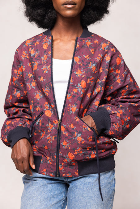 Person wearing a floral-patterned jacket with orange flowers on a maroon background