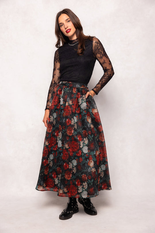 Woman wearing a black lace top and floral skirt on a white background