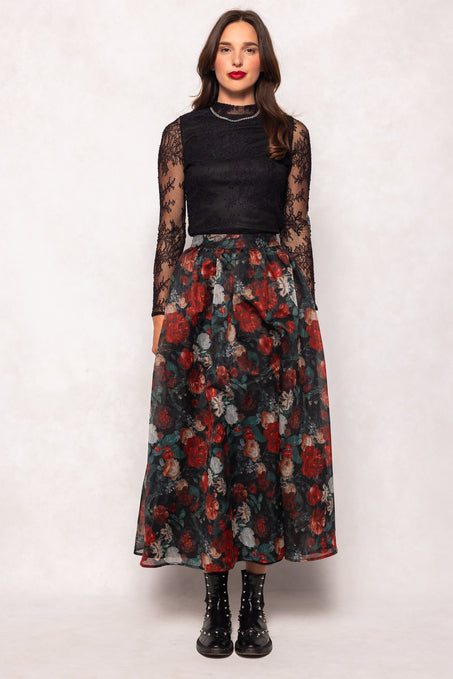 Woman wearing a black top and floral skirt on a white background