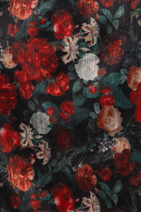 Close-up of a floral pattern with red, white, and green flowers on a dark background