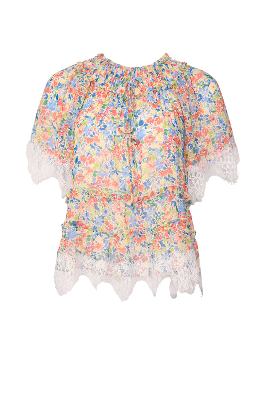 The Verona Top in Vibrant Yarrow by Ivy City Co is a short-sleeve blouse with an orange, blue, and yellow yarrow print, featuring a ruffled neckline plus white lace trim on the sleeves and hem.