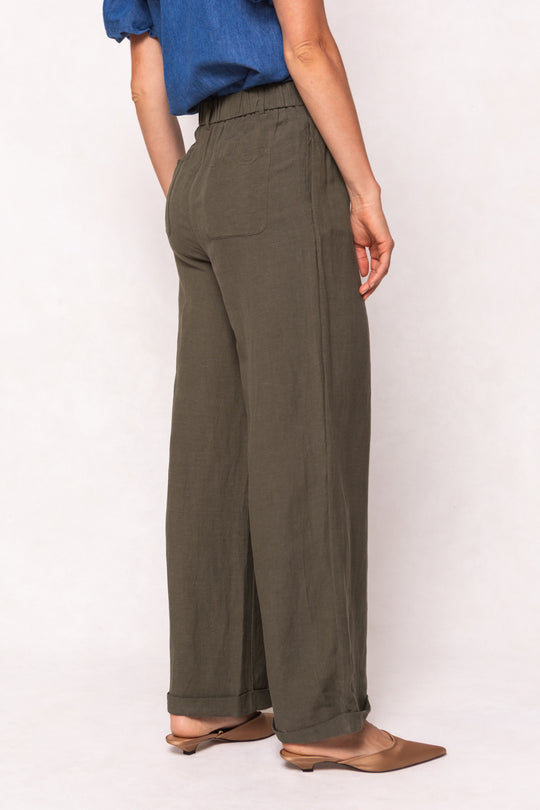 A woman wearing Ivy City Cos Veronica Pants in Green, featuring a wide-leg silhouette and an elastic waistband.