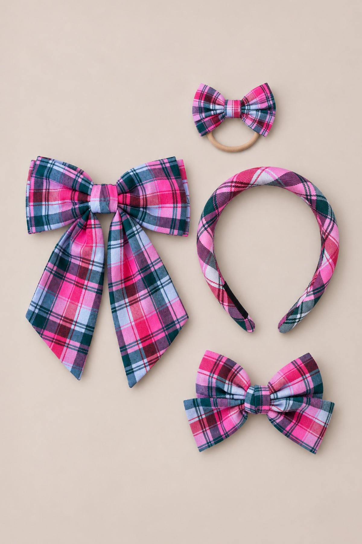 Showcased on a neutral background, Ivy City Co’s “Hair Bows in Vibrant Plaid” set includes four pink plaid accessories: a statement large bow with long tails, a petite clip-on bow, a matching headband, and a charming bow hair tie—perfect festive accents for the holidays.